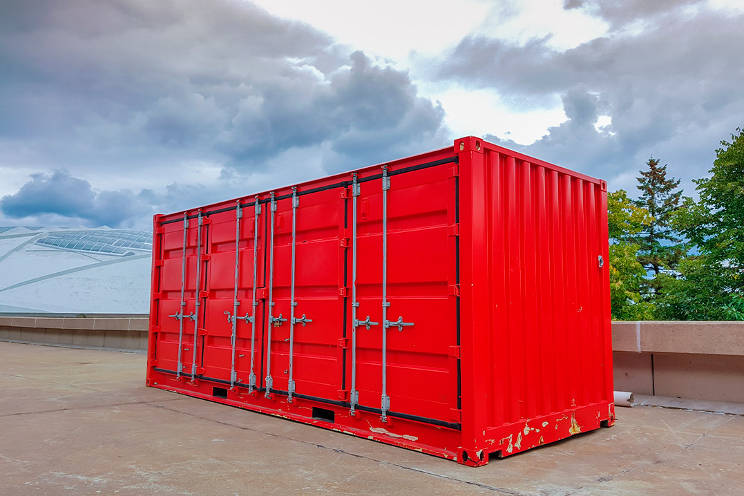 A red shipping container placed on a concrete surface, illustrating options for new and used containers in the market.