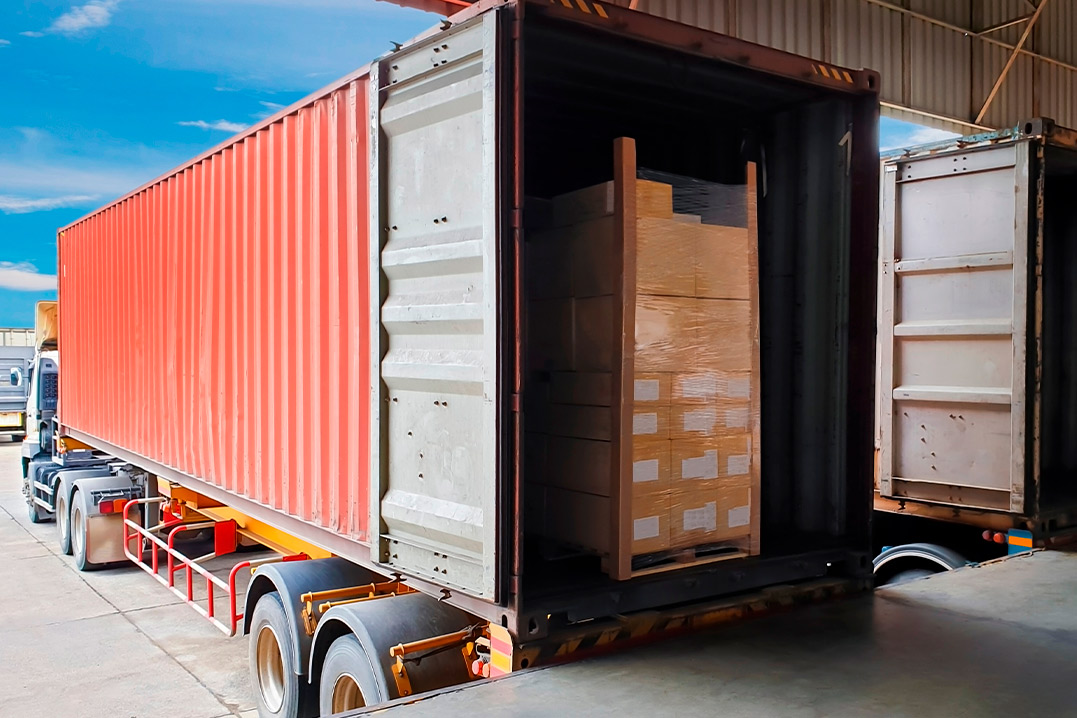 A large truck transporting a shipping container, symbolizing options for new and used containers in business logistics.