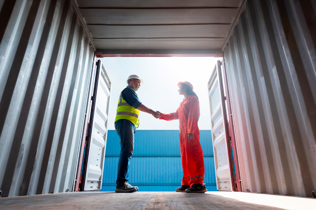 Two people engaged in a handshake within a shipping container, representing a transaction in Texas.