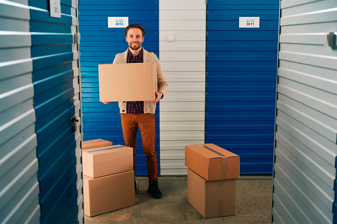 A man with a box in a storage unit, highlighting the strategic financial advantages of 40-foot storage containers for businesses.