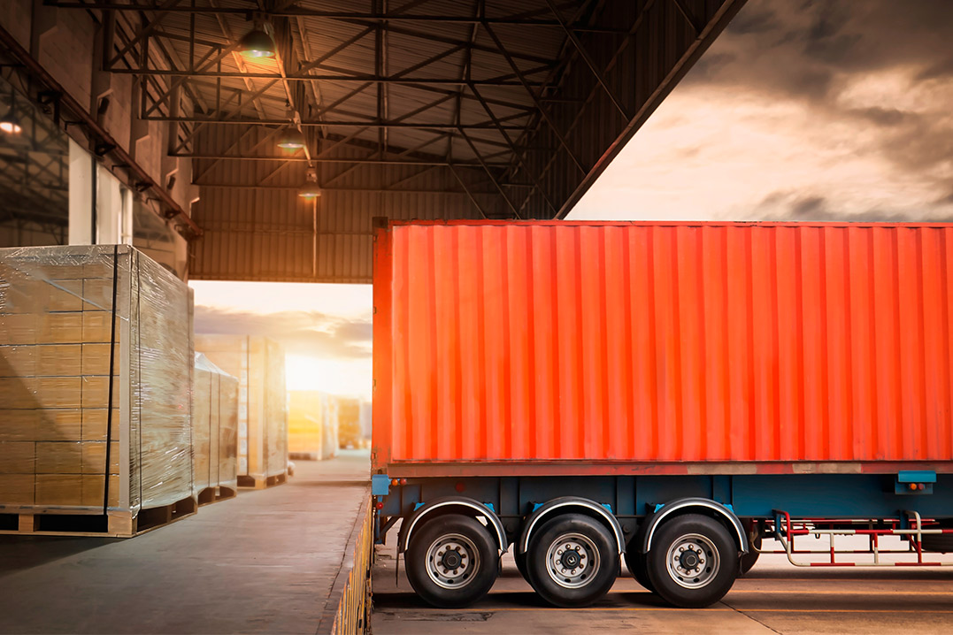 CTC distribution A red container truck is parked outside a warehouse, emphasizing duty-free warehousing services in McAllen for trade savings.