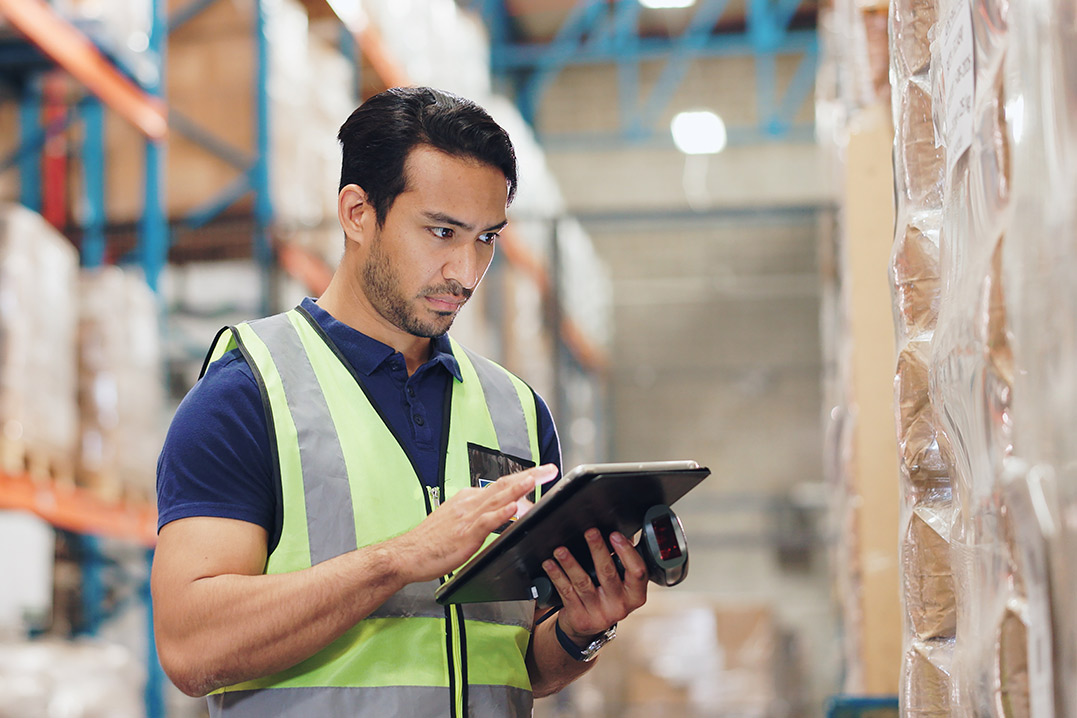 A warehouse worker uses a tablet, highlighting how 3PL bonded warehousing enhances cross-border logistics efficiency.