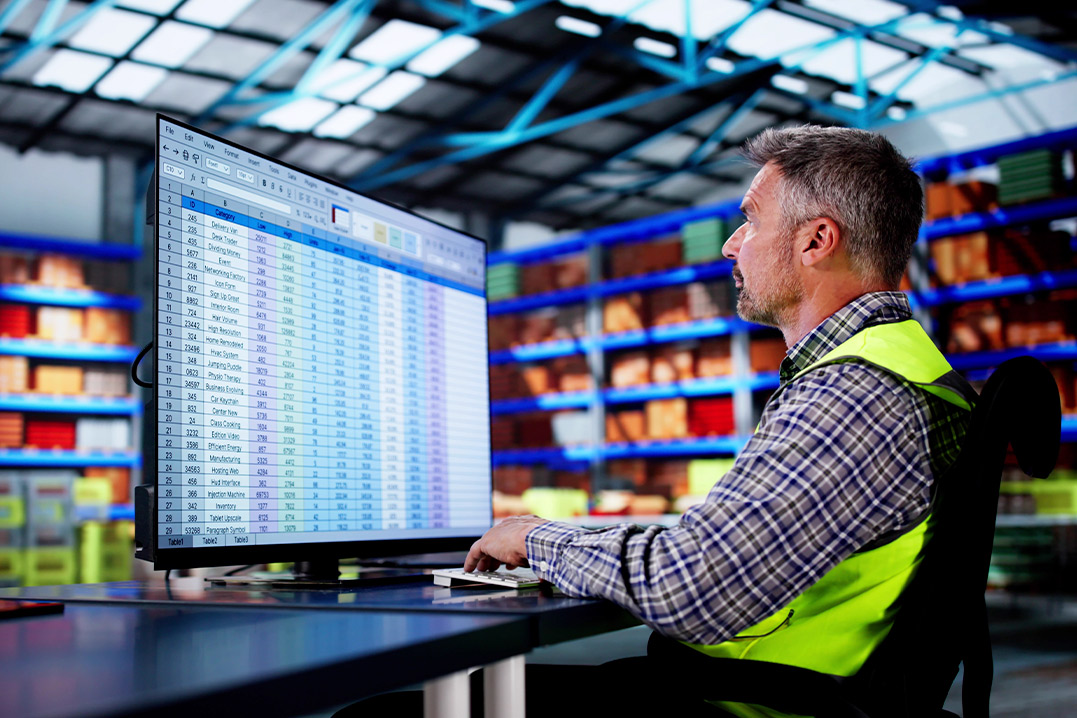 A man wearing a safety vest operates a computer, reviewing the compliance checklist for CBP Bonded Warehouse requirements.
