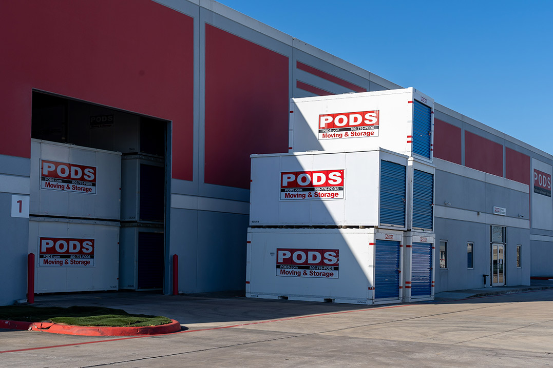 Stacked shipping containers inside a spacious warehouse, available for sale in South Texas.