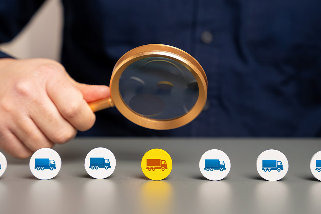 A magnifying glass held by a person focuses on various icons on a table, representing bonded warehouse concepts for importers.
