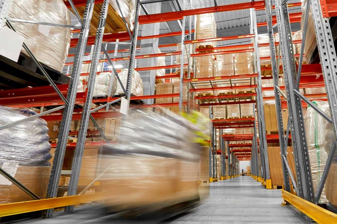  Inside a warehouse, shelves are lined with boxes and pallets, showcasing bonded warehousing for international e-commerce inventory.