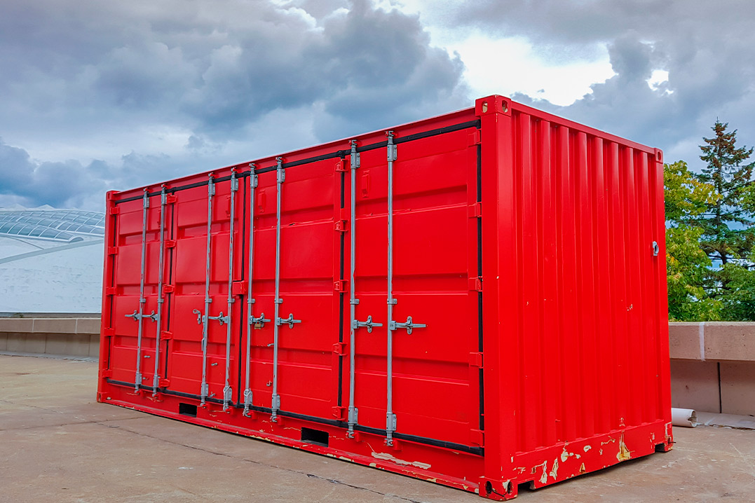 A red container positioned on a concrete floor, suitable for rental at construction sites this spring.