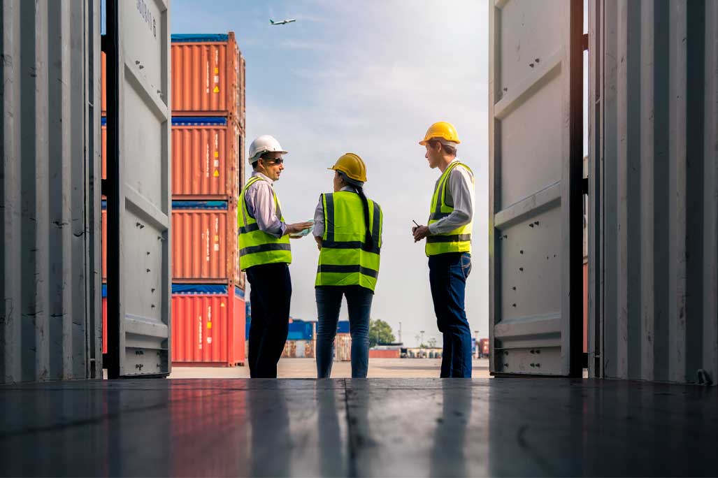 Group of staff worker standing and checking the containers box from cargo ship for export and import
