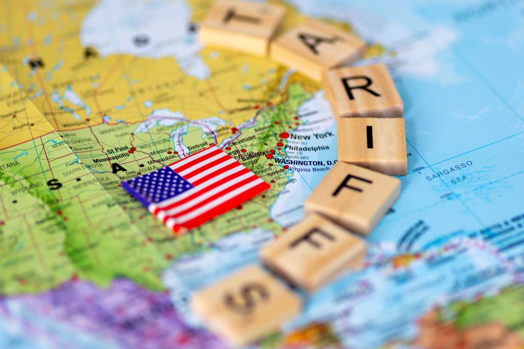 A map of the United States of America and the American flag with letter wooden tiles forming the word tariffs. A US tariffs concept.