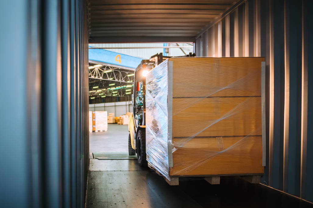 Warehouse Staff Driving Forklift to Move Carton Pallets for Export Process, Showing Industrial Logistics in Action with Proper Safety Measures